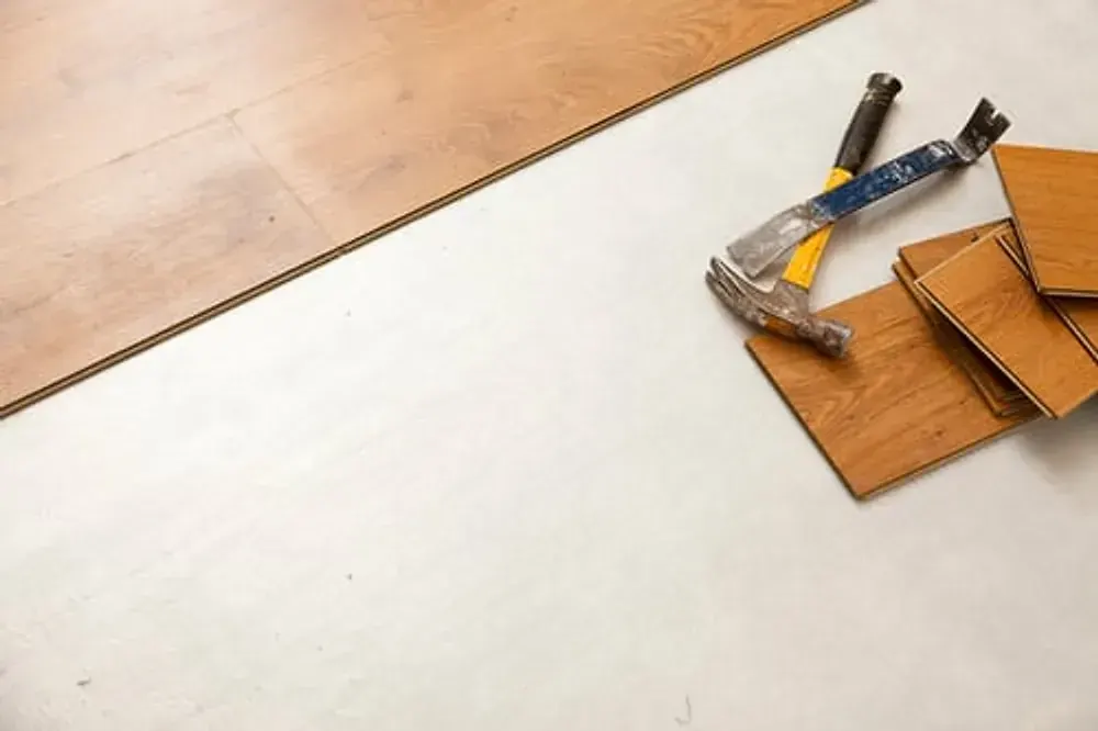 Laminate flooring planks and installation tools laid out on a subfloor in Vacaville, CA